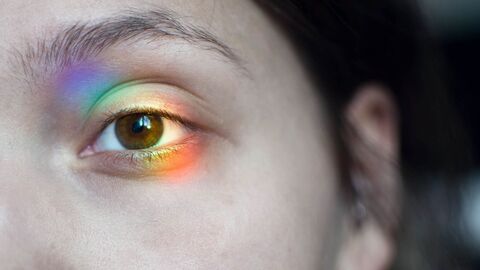 Auge einer Frau mit Lichtschimmer in Regenbogenfarben
