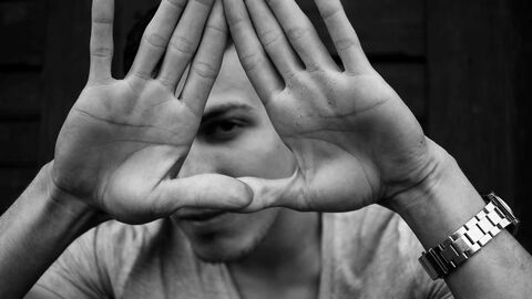 Mann hält Hände abwehrend vor sein Gesicht